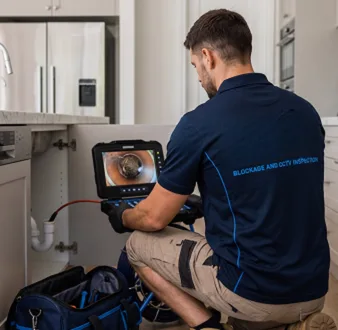 Plumber clearing a blocked toilet in a Gladesville bathroom